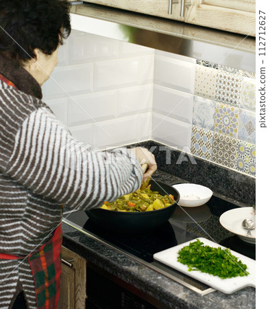 Elderly Woman Cooking Vegetables 112712627