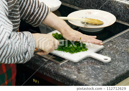 Elderly Woman Chopping Parsley 112712629