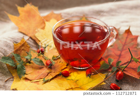 A cup of rose hip tea with fresh berries in a glass cup. Vintage background, selective focus A cup of rose hip tea with fresh berries in a glass cup. Vintage background, selective focus 112712871