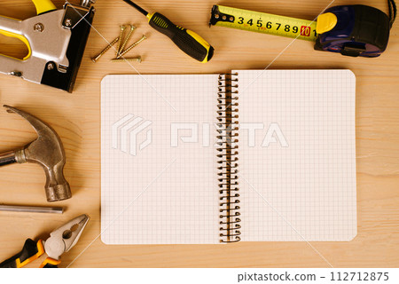 Notepad surrounded by dusty tools on an old wooden background. View from above. workplace Notepad surrounded by dusty tools on an old wooden background. View from above. workplace 112712875