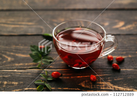 A cup of rose hip tea with fresh berries in a glass cup on dark wood background. Vintage background, selective focus 112712889