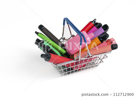 A set of colorful disposable electronic cigarettes of different shapes in a grocery basket on a white background with copy space. Concept of modern smoking. A set of colorful disposable electronic cigarettes of different shapes in a grocery basket on a white background with copy space. Concept of modern smoking. 112712900