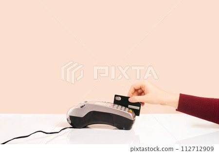 Customer hand near bar counter make payment use black credit card, hands device view, cashless method pay bills in on pink or coral background. minimalism 112712909