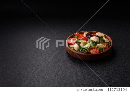 Delicious fresh caprese salad with mozzarella, tomatoes, greens with salt, spices and herbs 112713194