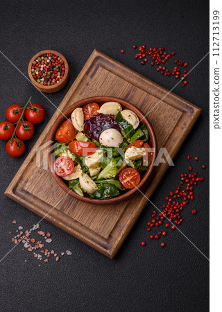 Delicious fresh caprese salad with mozzarella, tomatoes, greens with salt, spices and herbs 112713199