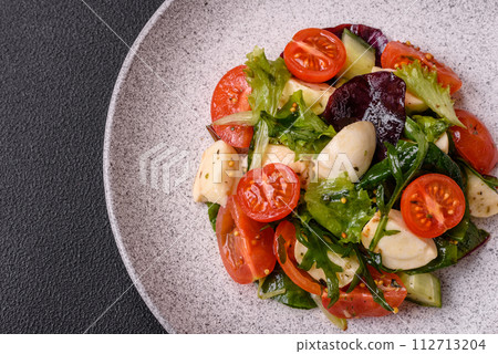 Delicious fresh caprese salad with mozzarella, tomatoes, greens with salt, spices and herbs Delicious fresh caprese salad with mozzarella, tomatoes, greens with salt, spices and herbs 112713204
