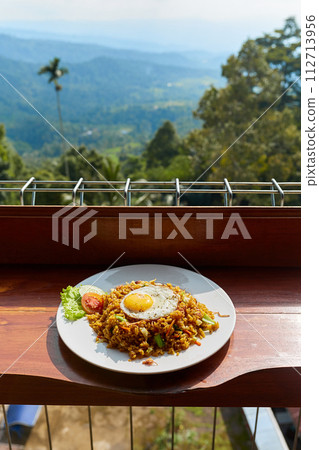 A plate of traditional Asian rice and egg breakfast at an outdoor cafe with a view of the mountains on the popular tourist island of Bali. 112713956