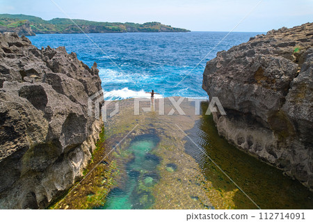 A cliff broken by the wave of the ocean. Natural azure bathing pool in the middle of the rock. A popular tourist spot on the island of Nusa Penida in Indonesia. 112714091