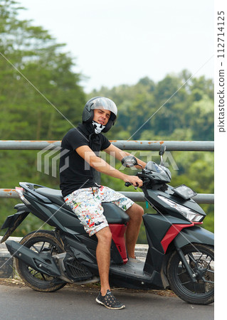 A man sits in a rocking-egg in a straw pergola enjoying the sunset A man sits in a rocking-egg in a straw pergola enjoying the sunset 112714125