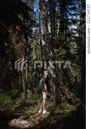 A man sits in a rocking-egg in a straw pergola enjoying the sunset 112714127