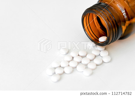 Medication Close-Up: White Pills and Brown Glass Vial Arranged on Table, Copy Space, Close-Up, Healthcare Concept.. 112714782