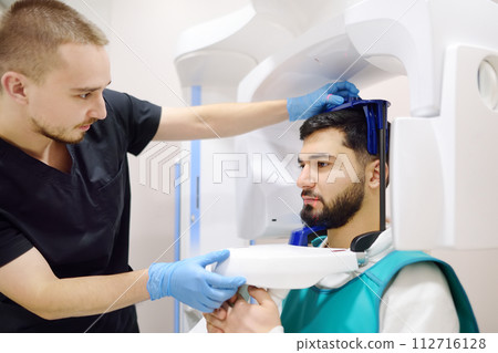 Doctor dentist are going to do a digital x-ray with man patient in dentistry clinic. Panoramic radiography. Modern professional dental equipment for hospital, clinic, medical center. 112716128