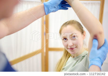 Young woman at an appointment with rheumatologist talks about pain symptom and bruises. Orthopedic doctor examines a patient. 112716142