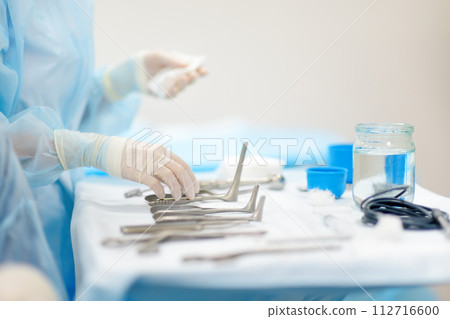 A nurse hands surgical instruments to a doctor during maxillofacial surgery operation. Sterile medical tools 112716600