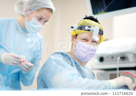 Surgeons are during maxillofacial operation using microscope and endoscope in modern hospital. Teamwork of doctors. Maxillofacial surgery. Surgeons are during maxillofacial operation using microscope and endoscope in modern hospital. Teamwork of doctors. Maxillofacial surgery. 112716620