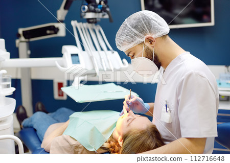 Dentist and patient at modern medical center. Doctor treats a young woman teeth in hospital. Practitioner examines the patient before orthodontists or prosthetics treatment. 112716648