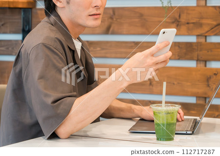 亞洲年輕男子在咖啡館使用智慧型手機和電腦 亞洲年輕男子在咖啡館使用智慧型手機和電腦 112717287