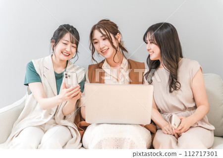 Women, friends, mom friends, and colleagues who use smartphones and laptops together at home 112717301
