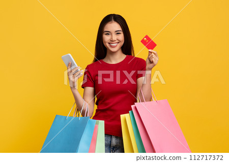 Happy asian woman with phone, credit card and shopping bags Happy asian woman with phone, credit card and shopping bags 112717372