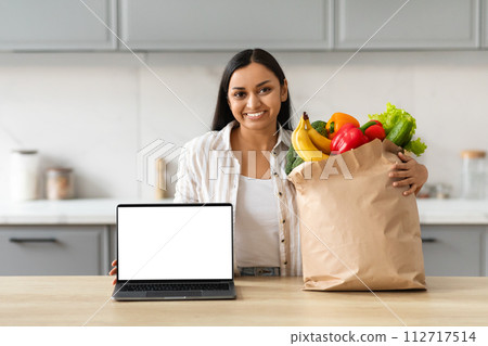 Happy young indian woman order grocery online, showing laptop Happy young indian woman order grocery online, showing laptop 112717514