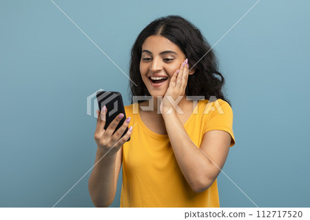 Excited lady with smartphone on teal 112717520