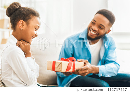African-american father giving gift to daughter at home 112717537
