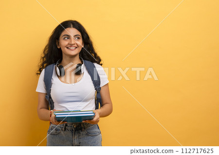 Studious woman holding books and looking up 112717625