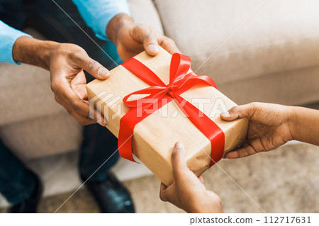 Father hands giving birthday gift to daughter Father hands giving birthday gift to daughter 112717631