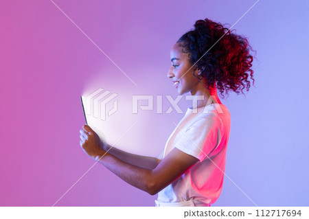 Content black woman with tablet glowing on purple-pink background Content black woman with tablet glowing on purple-pink background 112717694