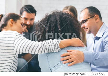 Addicted people comforting upset woman at therapy session 112717772