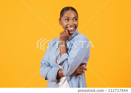 Black woman in denim shirt touching chin looking aside, studio 112717844