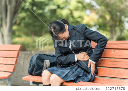 Junior high school and high school female students crouching down on a park bench with abdominal pain (menstrual pain, poor physical condition, painful, painful) 112717878