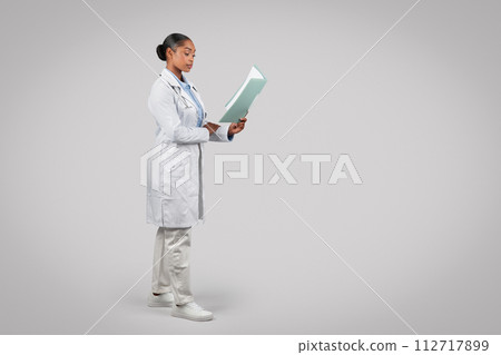 Focused black young woman doctor in white coat, work with papers 112717899