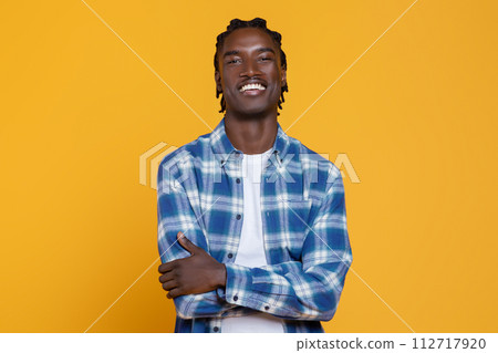 Handsome Young Black Man Posing With Folded Arms On Yellow Studio Background Handsome Young Black Man Posing With Folded Arms On Yellow Studio Background 112717920