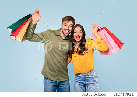 Cheerful couple celebrating shopping spree with colorful bags Cheerful couple celebrating shopping spree with colorful bags 112717921