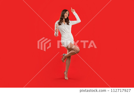 lady holds flute of sparkling wine dancing on red background 112717927