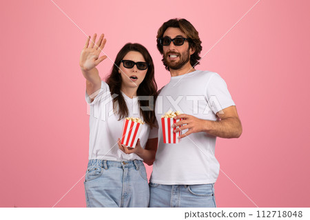 Enthusiastic couple wearing 3D glasses, excitedly reaching out towards something unseen Enthusiastic couple wearing 3D glasses, excitedly reaching out towards something unseen 112718048