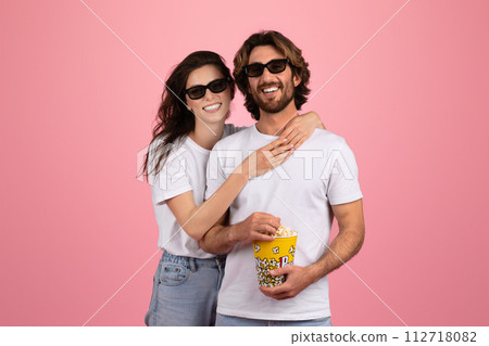 Cheerful couple in casual wear and 3D glasses smiling and sharing popcorn 112718082