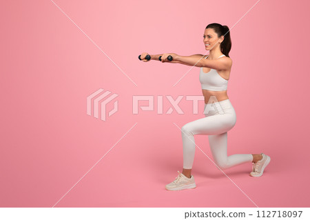 Happy strong millennial caucasian woman in white sportswear, squats with dumbbells 112718097