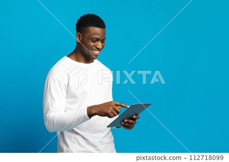 Happy young black guy using digital tablet Happy young black guy using digital tablet 112718099