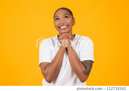 African American Woman Praying Holding Hands Together Over Yellow Backdrop African American Woman Praying Holding Hands Together Over Yellow Backdrop 112718102