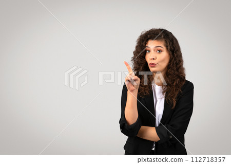 Curious businesswoman gesturing with finger, pointing at free space Curious businesswoman gesturing with finger, pointing at free space 112718357