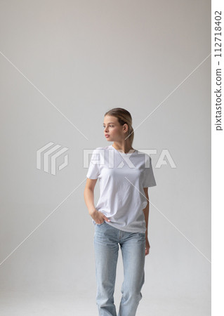 Beautiful blonde woman in a white T-shirt and blue jeans posing on a white background Beautiful blonde woman in a white T-shirt and blue jeans posing on a white background 112718402