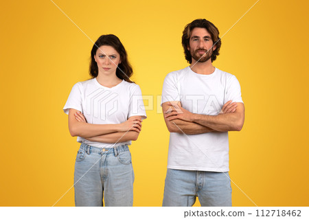 Determined young woman and man standing with arms crossed, exuding confidence and readiness 112718462