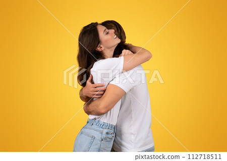 An intimate moment as a woman with long brown hair hugs a man from behind 112718511