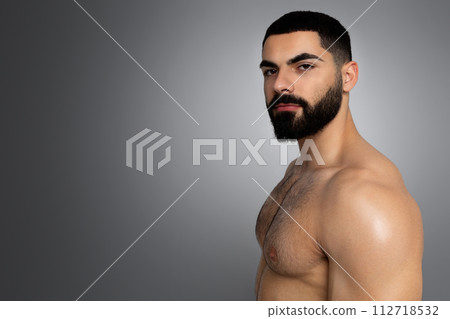 Handsome naked middle eastern young man posing on grey 112718532