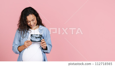 Happy pregnant woman showing ultrasound image of her baby Happy pregnant woman showing ultrasound image of her baby 112718565