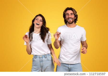 Radiant young woman and man in white tees laughing and dancing Radiant young woman and man in white tees laughing and dancing 112718597
