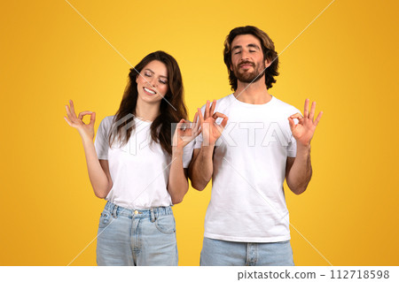 Contented man and woman with closed eyes making OK signs, signaling approval Contented man and woman with closed eyes making OK signs, signaling approval 112718598