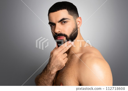 Cool photo of Middle Eastern guy posing shirtless on grey 112718608